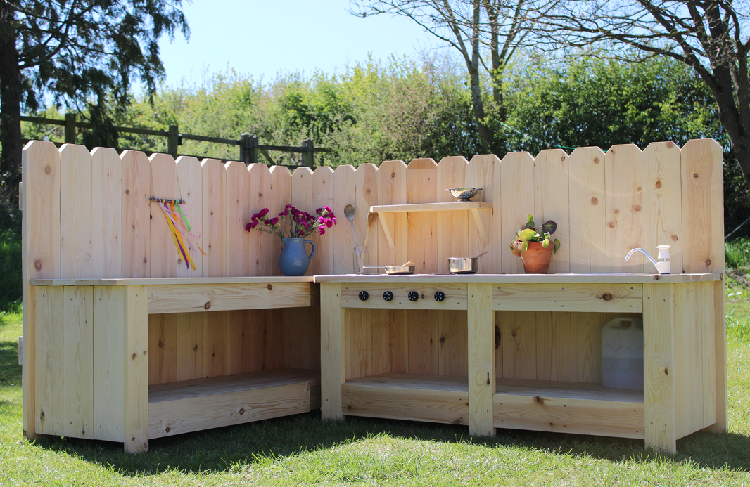 Wooden outdoor kitchen with grill and cabinets on a grassy area