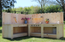 Wooden outdoor kitchen with grill and cabinets on a grassy area