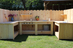 Wooden outdoor kitchen setup with cabinets and countertops in a backyard.
